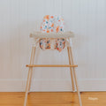Posture & Comfort Kit on an IKEA Antilop highchair: maple footrest, floral cushion cover and support insert