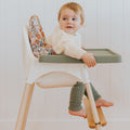 Toddler sitting on the cushion with feet resting on the maple footrest